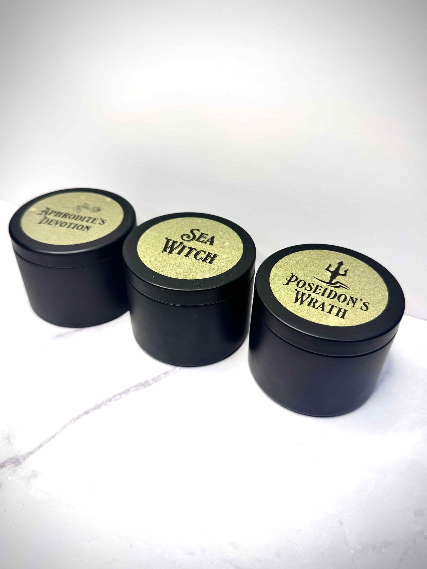 Three small black candles with labeled lids on a white background