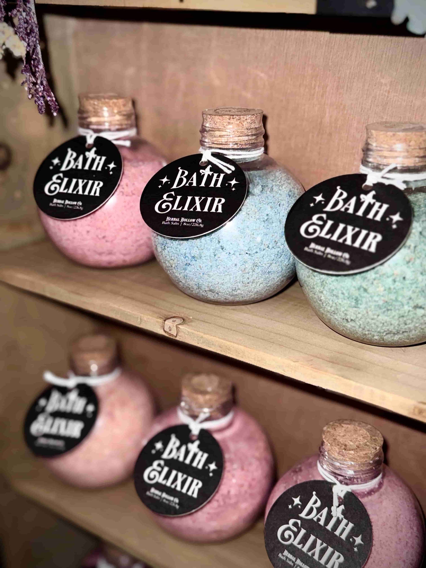 Herbal Hollow Co bath elixirs — lavender and sage scented bath salts in pink, blue, and green, packaged in witchy, whimsical, and  fantasy-themed potion bottles.