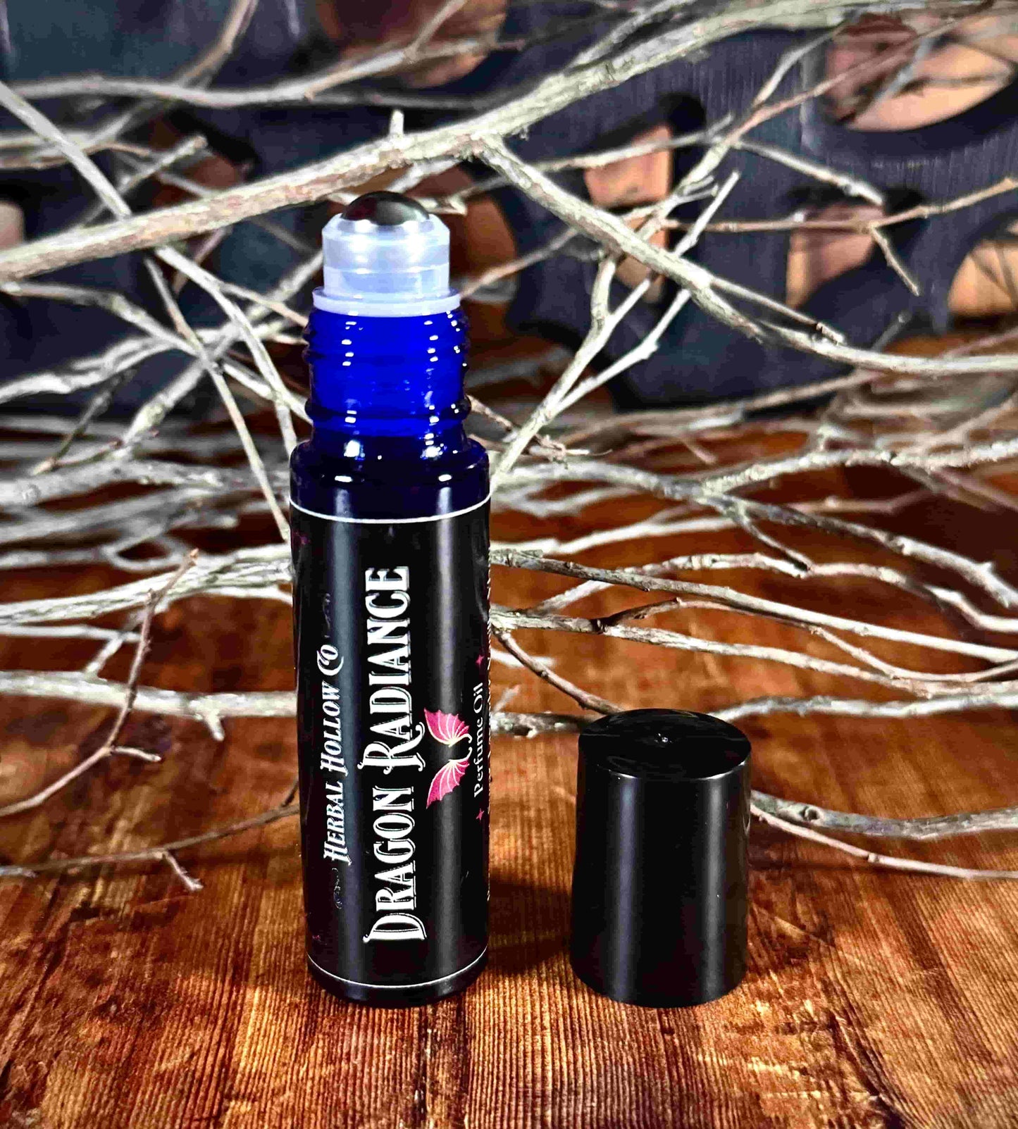 Image of small perfume bottle standing up with cap off. Dragon Radiance is a fantasy-inspired rollerball fragrance oil perfume, featuring a handcrafted magical vanilla, lavender, yang yang, amber, sandalwood, and musk scent in a portable glass bottle.