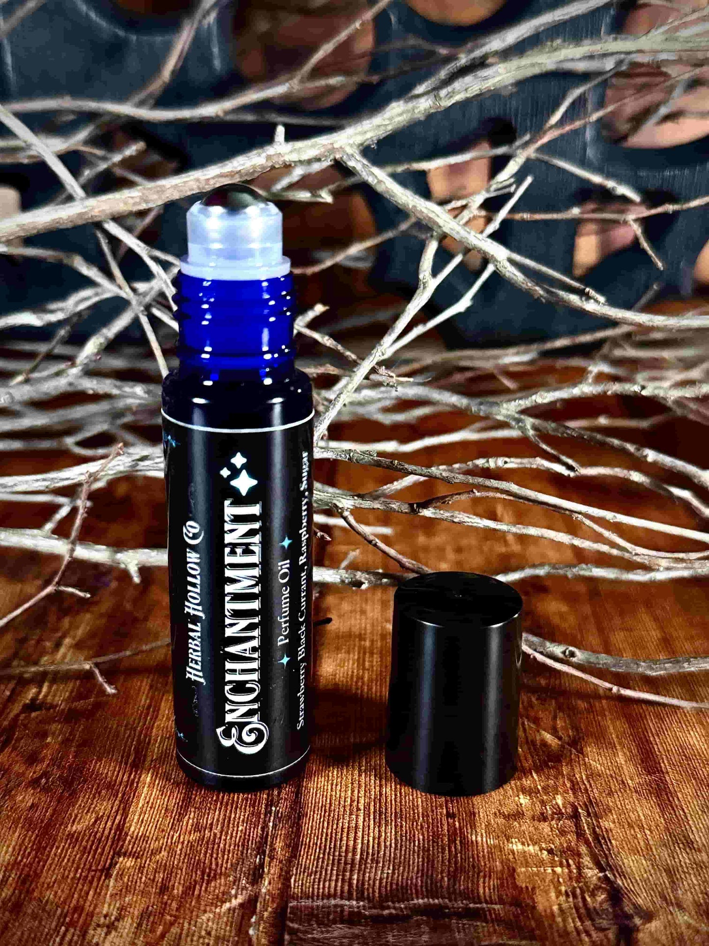 Image of small perfume bottle standing up with cap off. Enchantment is a fantasy-inspired rollerball fragrance oil perfume, featuring a handcrafted magical strawberry, black currant, raspberry, and sugar scent in a portable glass bottle.
