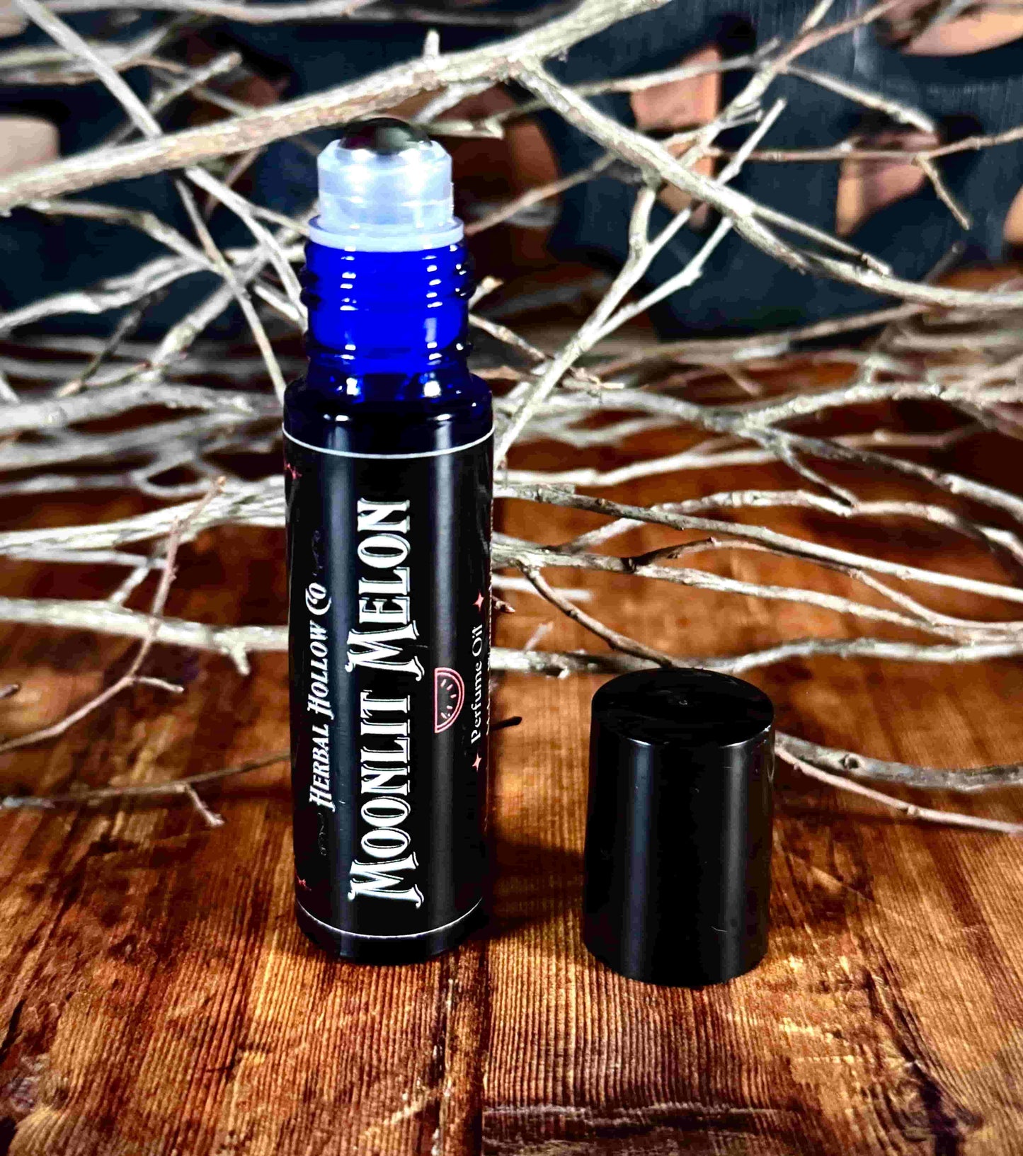 Image of small perfume bottle standing up with cap off. Moonlit Melon is a fantasy-inspired rollerball fragrance oil perfume, featuring a handcrafted magical watermelon scent in a portable glass bottle.
