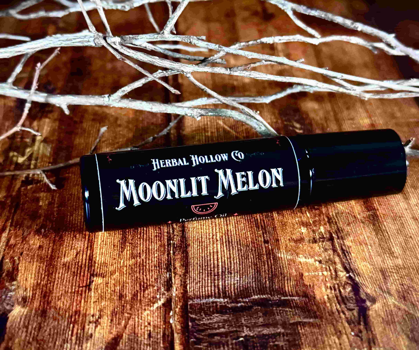 Image of small perfume bottle lying down. Moonlit Melon is a fantasy-inspired rollerball fragrance oil perfume, featuring a handcrafted magical watermelon scent.
