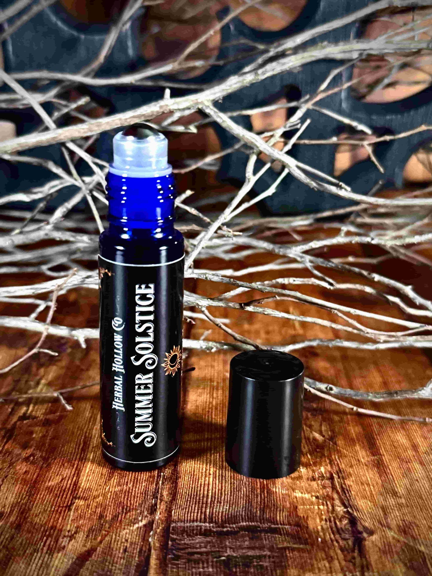 Image of small perfume bottle standing up with cap off. Summer Solstice is a fantasy-inspired rollerball fragrance oil perfume, featuring a handcrafted magical citrus, ozone, red and black currant, jasmine, and peach scent in a portable glass bottle.