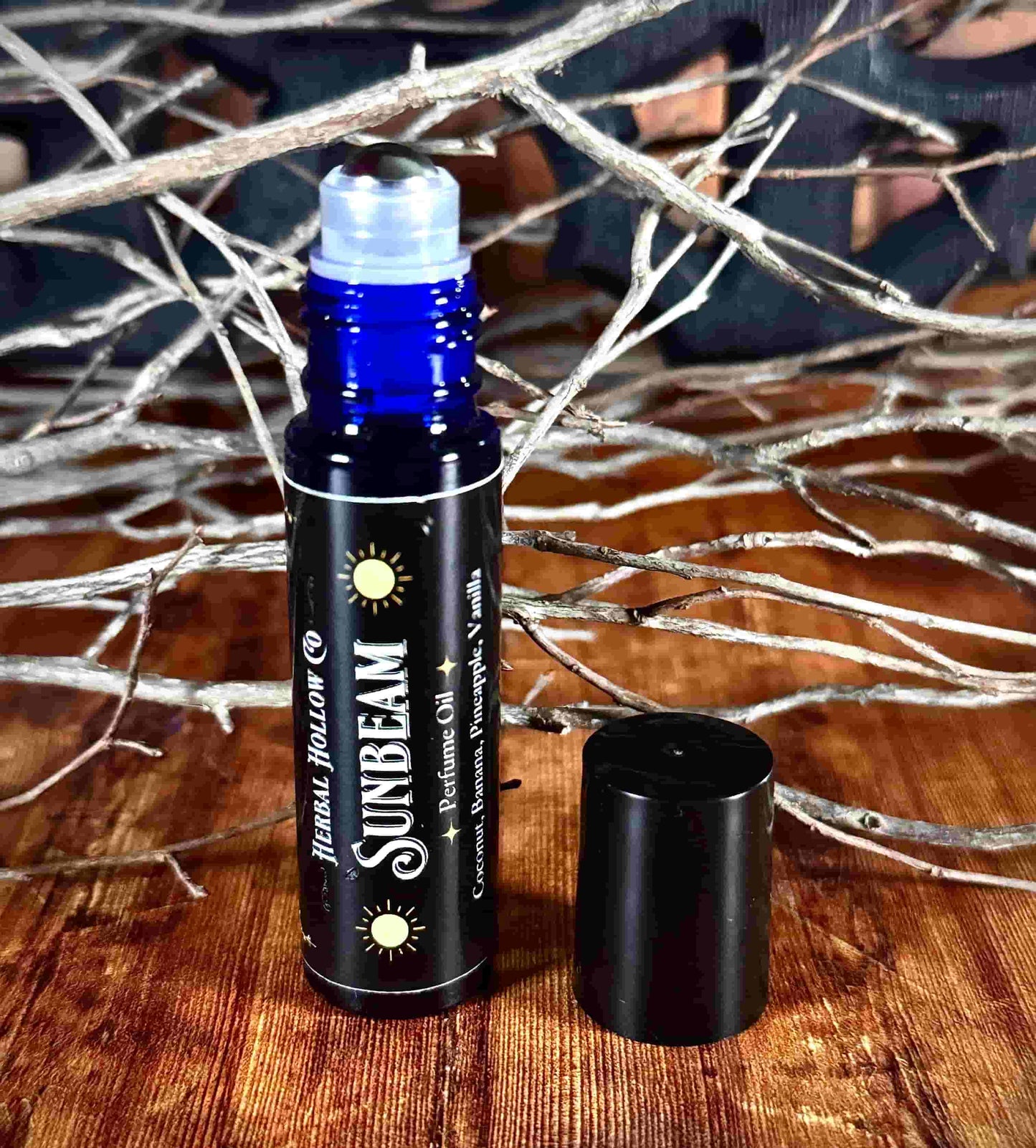 Image of small perfume bottle standing up with cap off. Sunbeam fantasy-inspired rollerball fragrance oil perfume, featuring a handcrafted magical coconut, pineapple, vanilla and banana scent in a portable glass bottle.