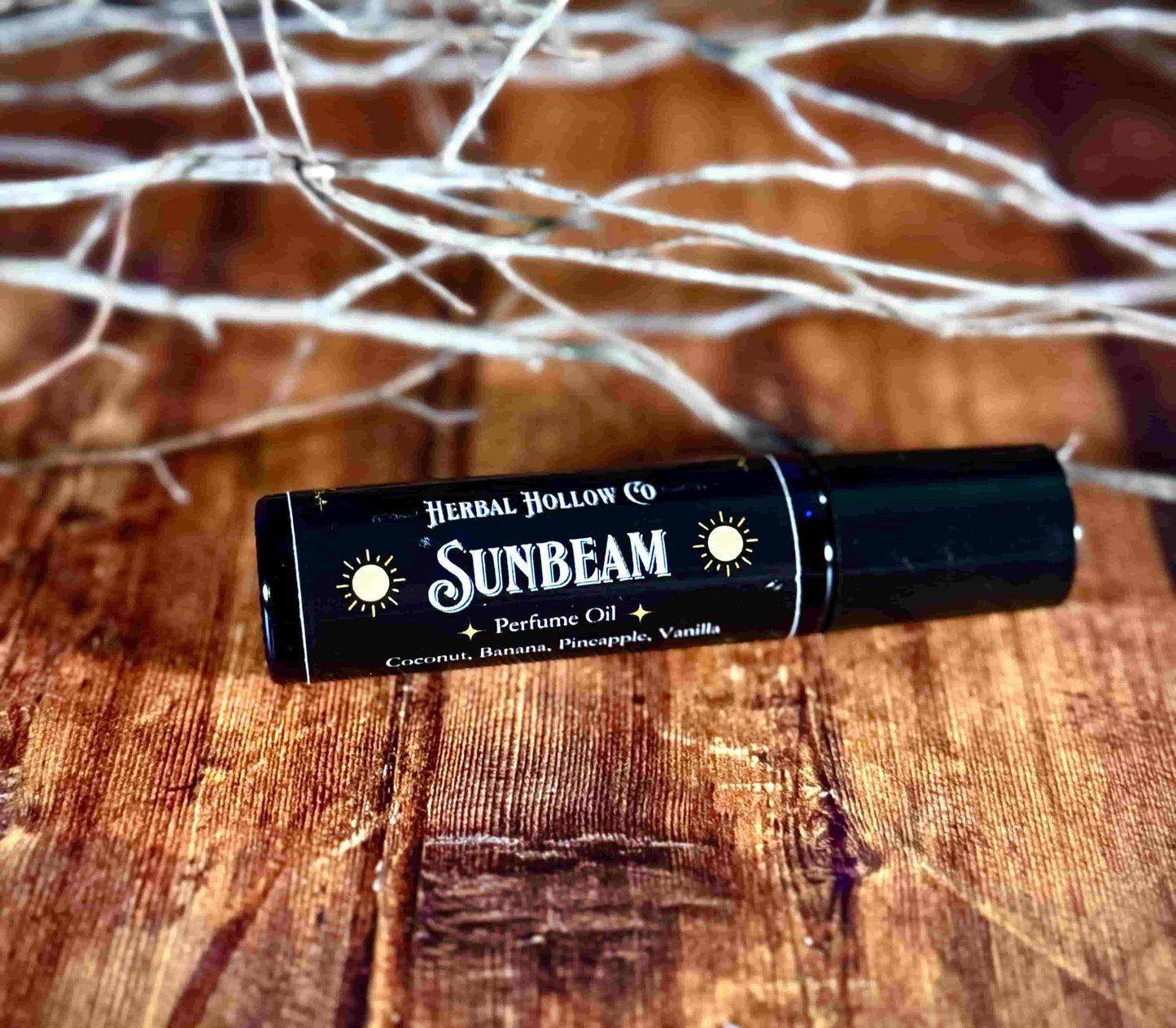 Image of small perfume bottle lying down. Sunbeam fantasy-inspired rollerball fragrance oil perfume, featuring a handcrafted magical coconut, pineapple, vanilla and banana scent.