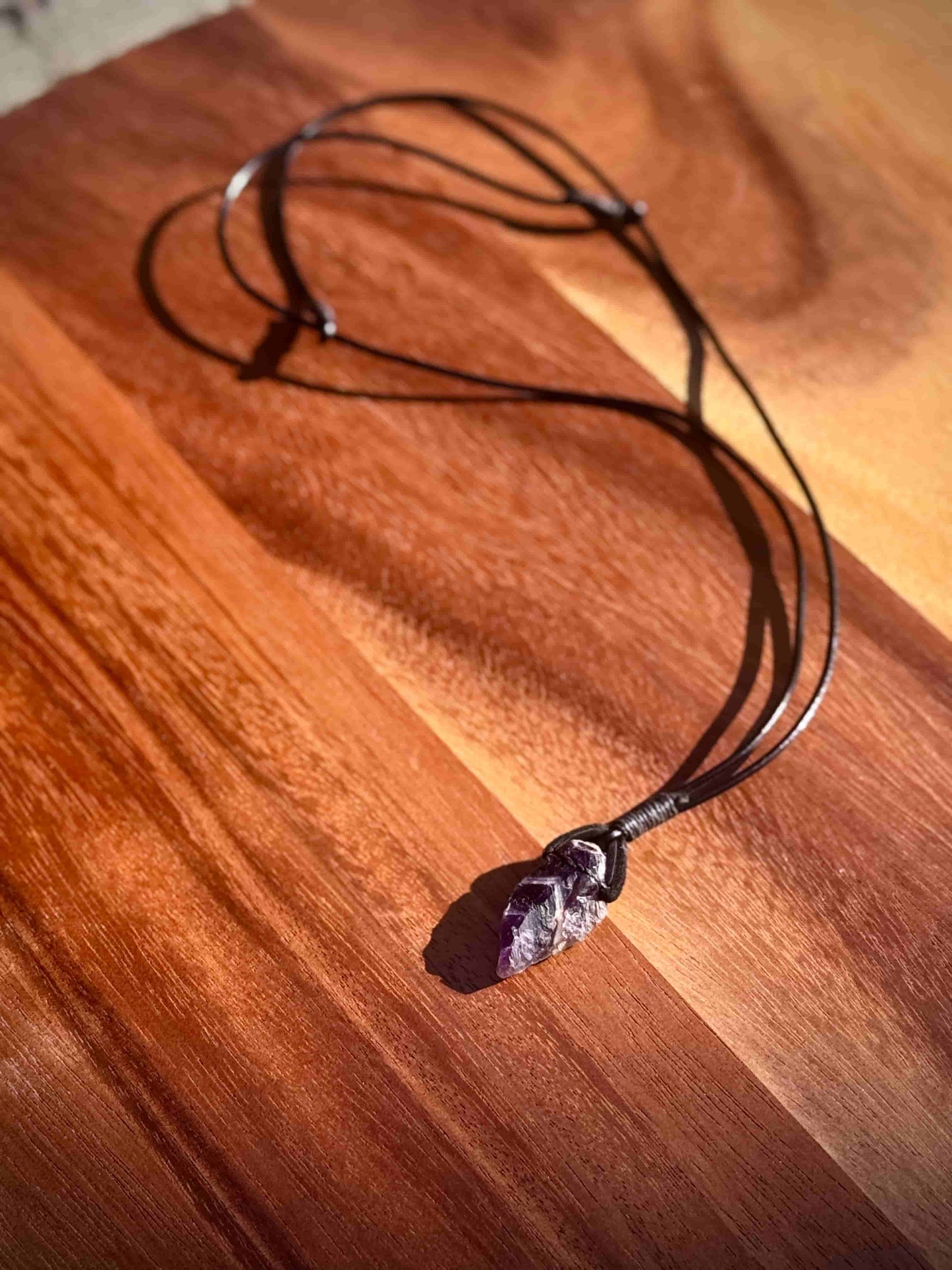 Dark purple Amethyst crystal necklace on a wooden surface
