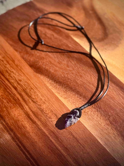 Dark purple Amethyst crystal necklace on a wooden surface