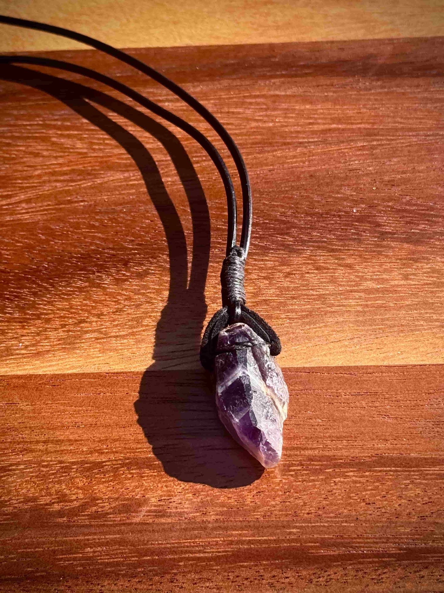 Amethyst crystal necklace on a wooden surface