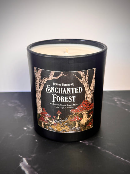 Candle in a black jar with 'Enchanted Forest' label on a dark surface