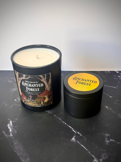 Large and small candles labeled 'Enchanted Forest' on a dark surface