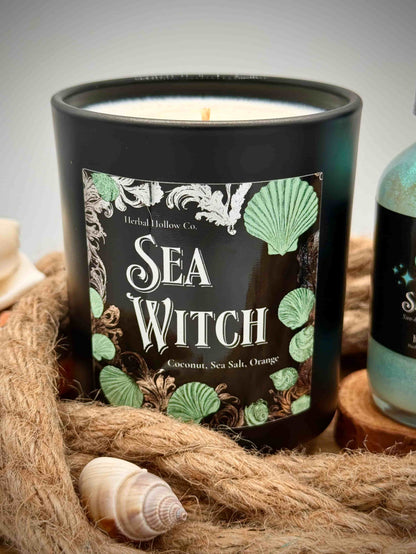 Candle labeled 'Sea Witch' with a shell and rope on a neutral background
