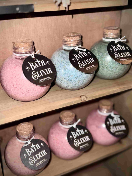 Herbal Hollow Co muscle soothing bath elixirs — lavender and sage scented bath salts in pink, blue, and green, packaged in witchy, whimsical, and  fantasy-themed potion bottles.