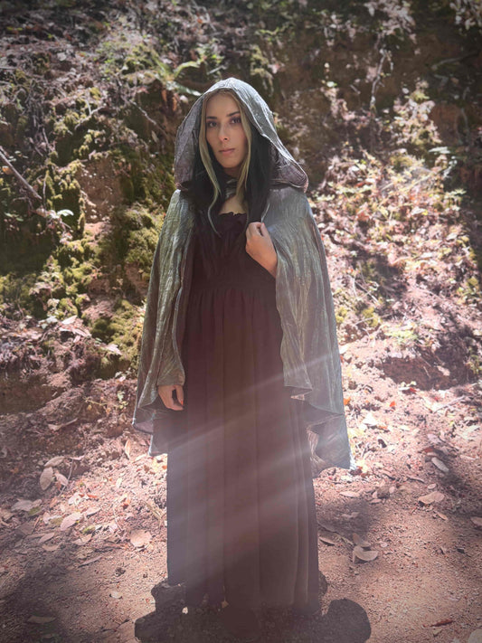 Person wearing a short tiered silver hooded cloak in a forest setting