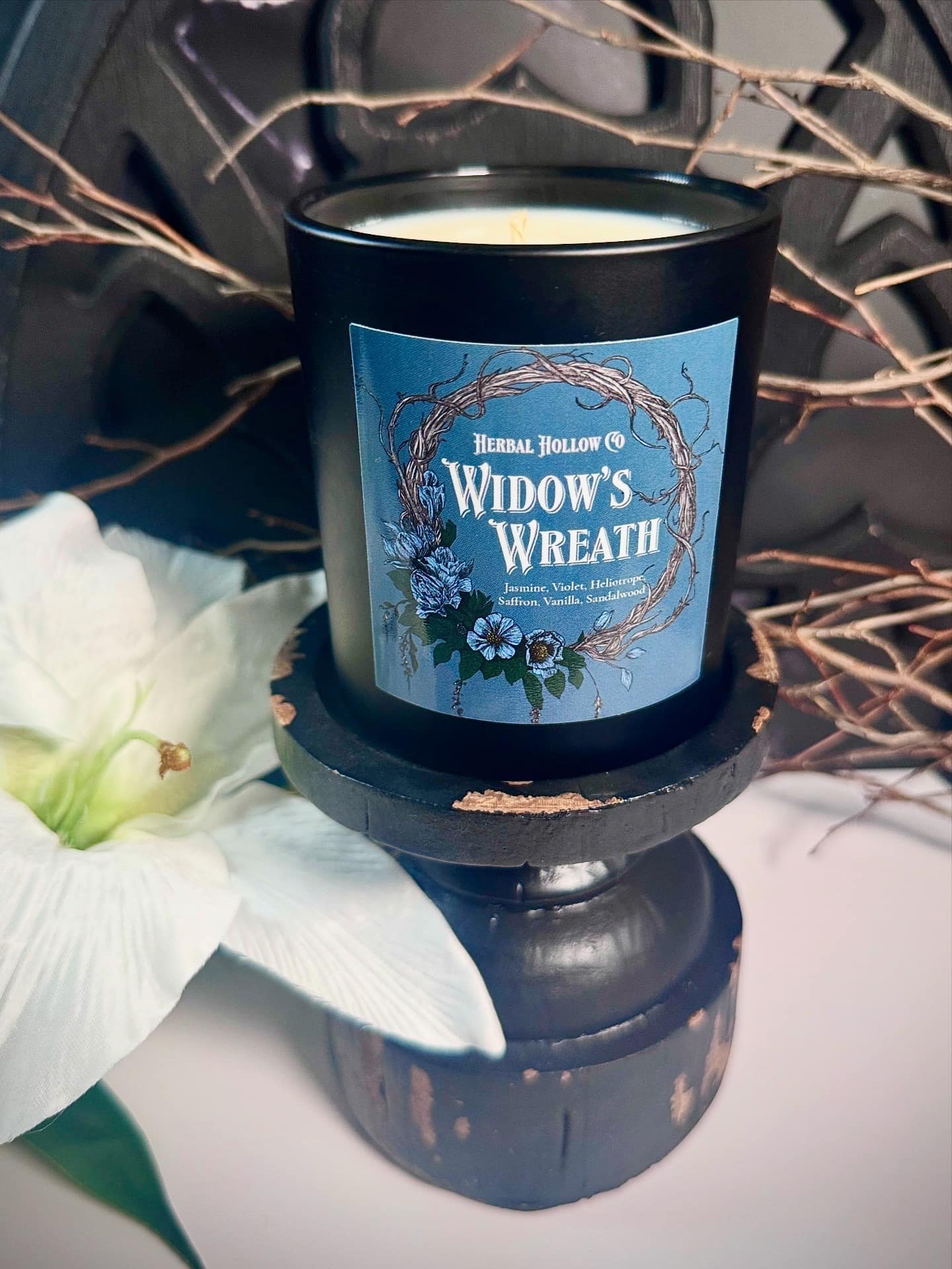 Candle labeled 'Widow's Wreath' with decorative elements on a white surface
