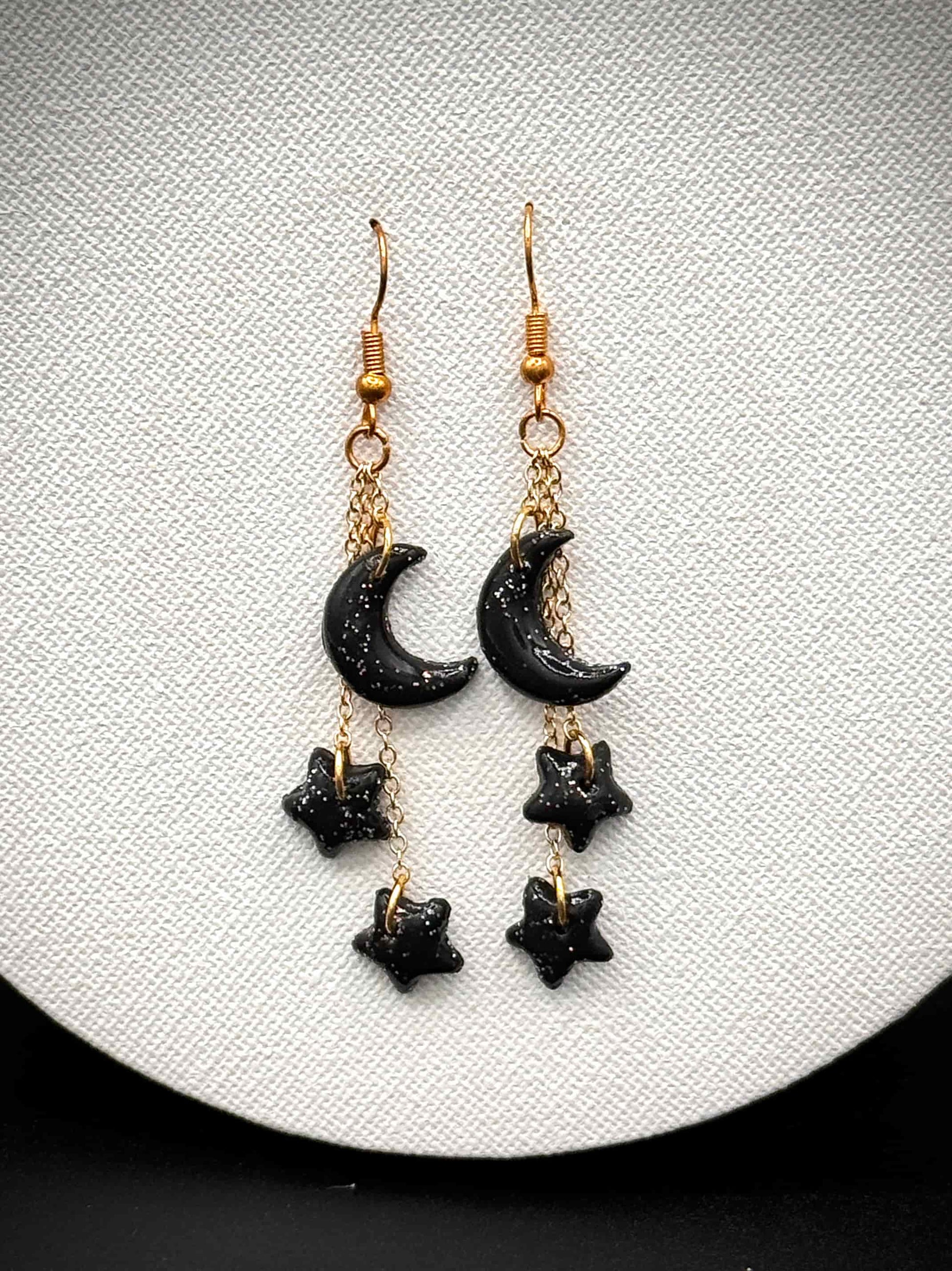 Black crescent moon and star with rainbow glitter earrings on gold hooks on a white background