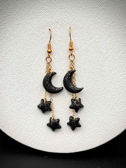 Black crescent moon and star with rainbow glitter earrings on gold hooks on a white background