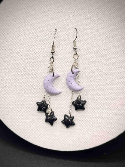 Pair of rainbow glitter purple moon and black star earrings on a white background