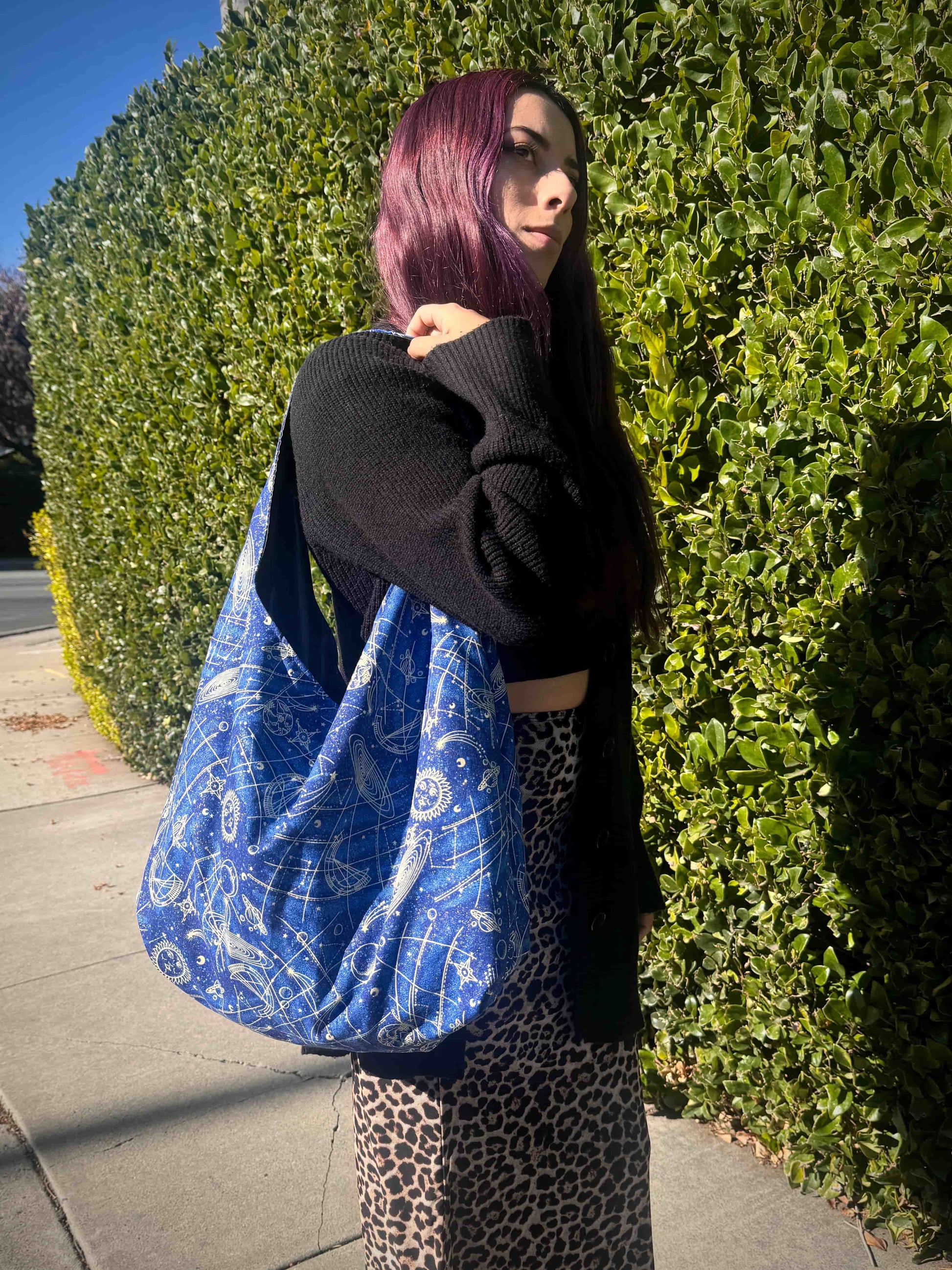 Person holding a blue and white celestial patterned bag outdoors.