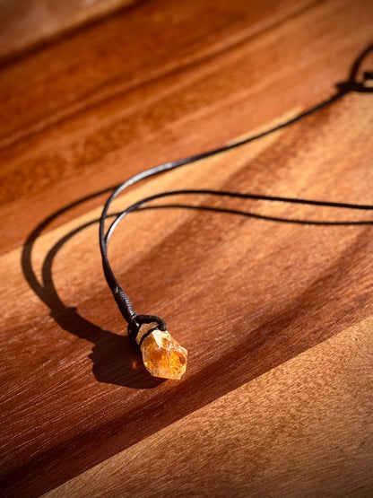 Orange citrine crystal with black leather band on a wooden background. 