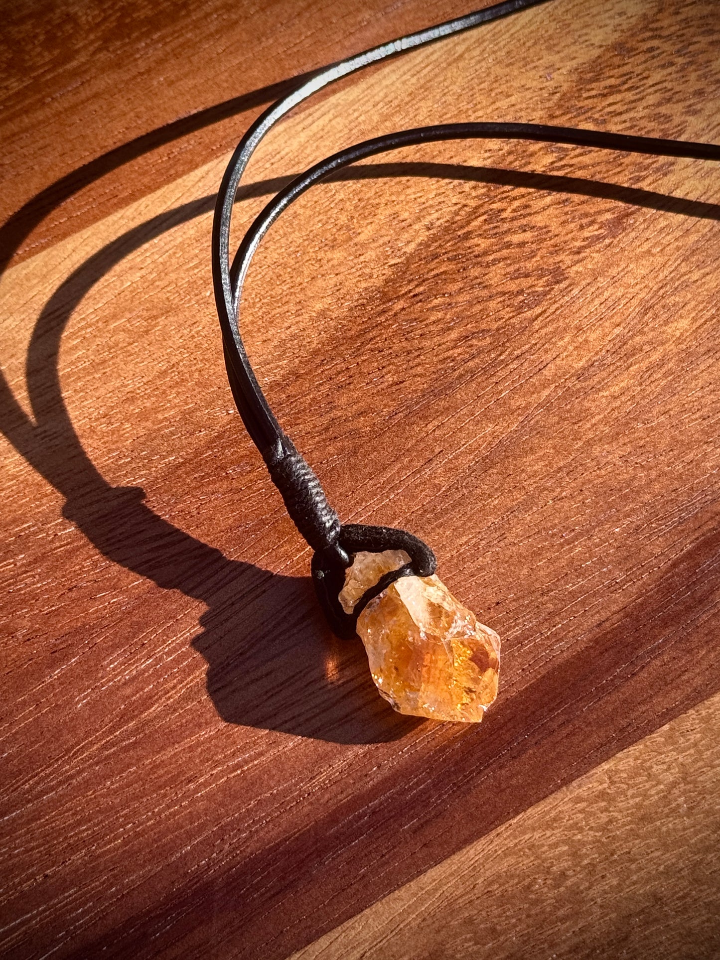 Close up of an Orange Citrine necklace with leather wrap on wooden background.