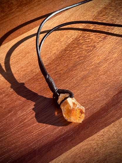 Close up of an Orange Citrine necklace with leather wrap on wooden background.
