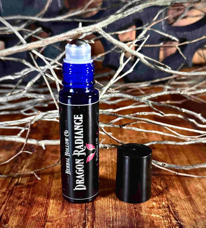 Image of small perfume bottle standing up with cap off. Dragon Radiance is a fantasy-inspired rollerball fragrance oil perfume, featuring a handcrafted magical vanilla, lavender, yang yang, amber, sandalwood, and musk scent in a portable glass bottle.