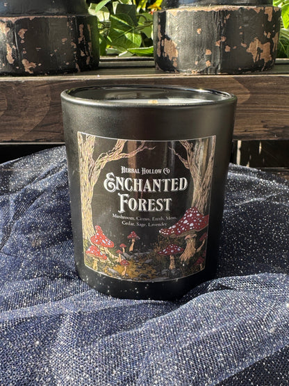 Candle labeled 'Enchanted Forest' on a wooden surface with a textured fabric background.