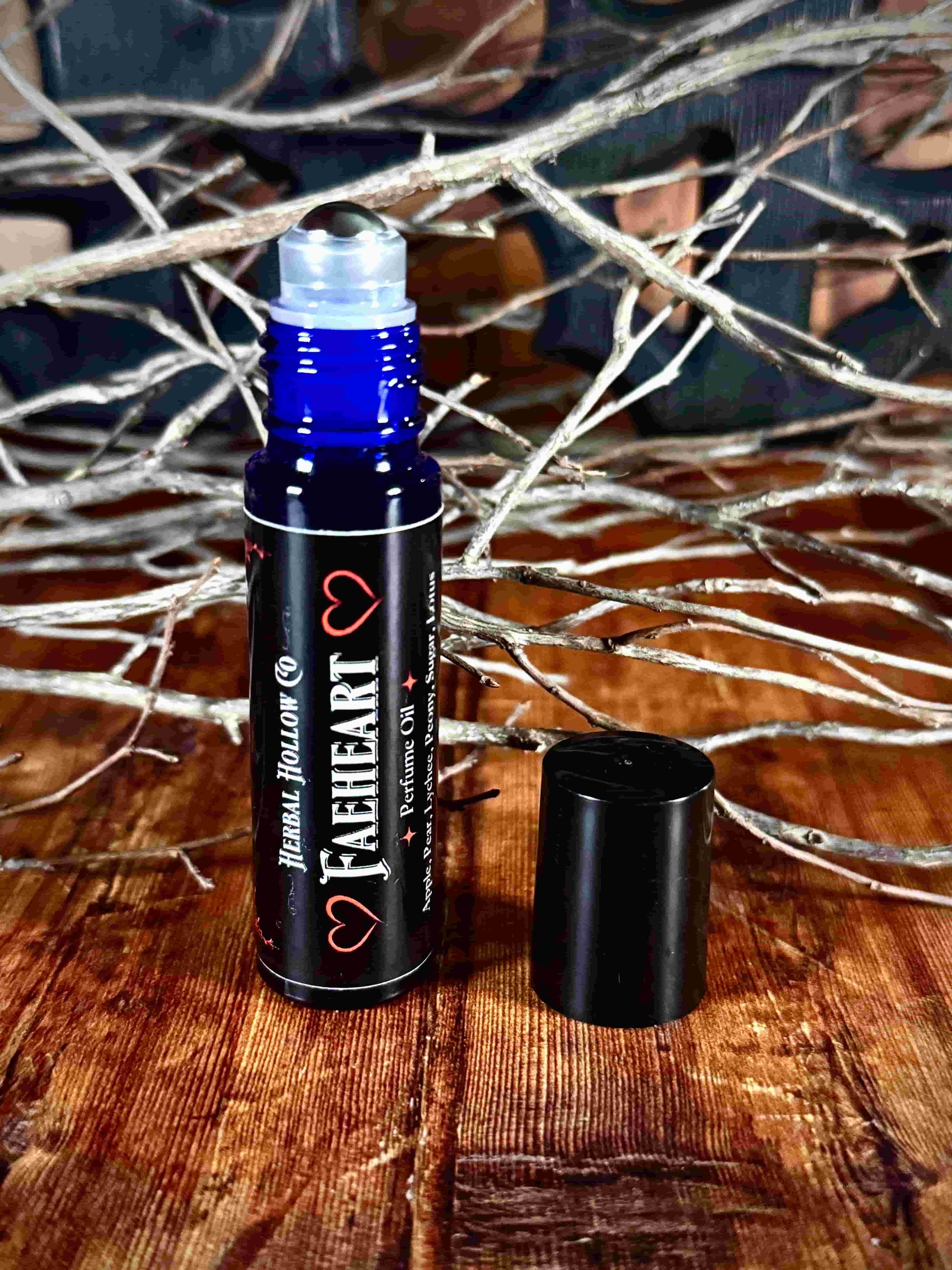Image of small perfume bottle standing up with cap off. Faeheart is a fantasy-inspired rollerball fragrance oil perfume, featuring a handcrafted magical lychee, pear, apple, peony, and lotus flower scent in a portable glass bottle.