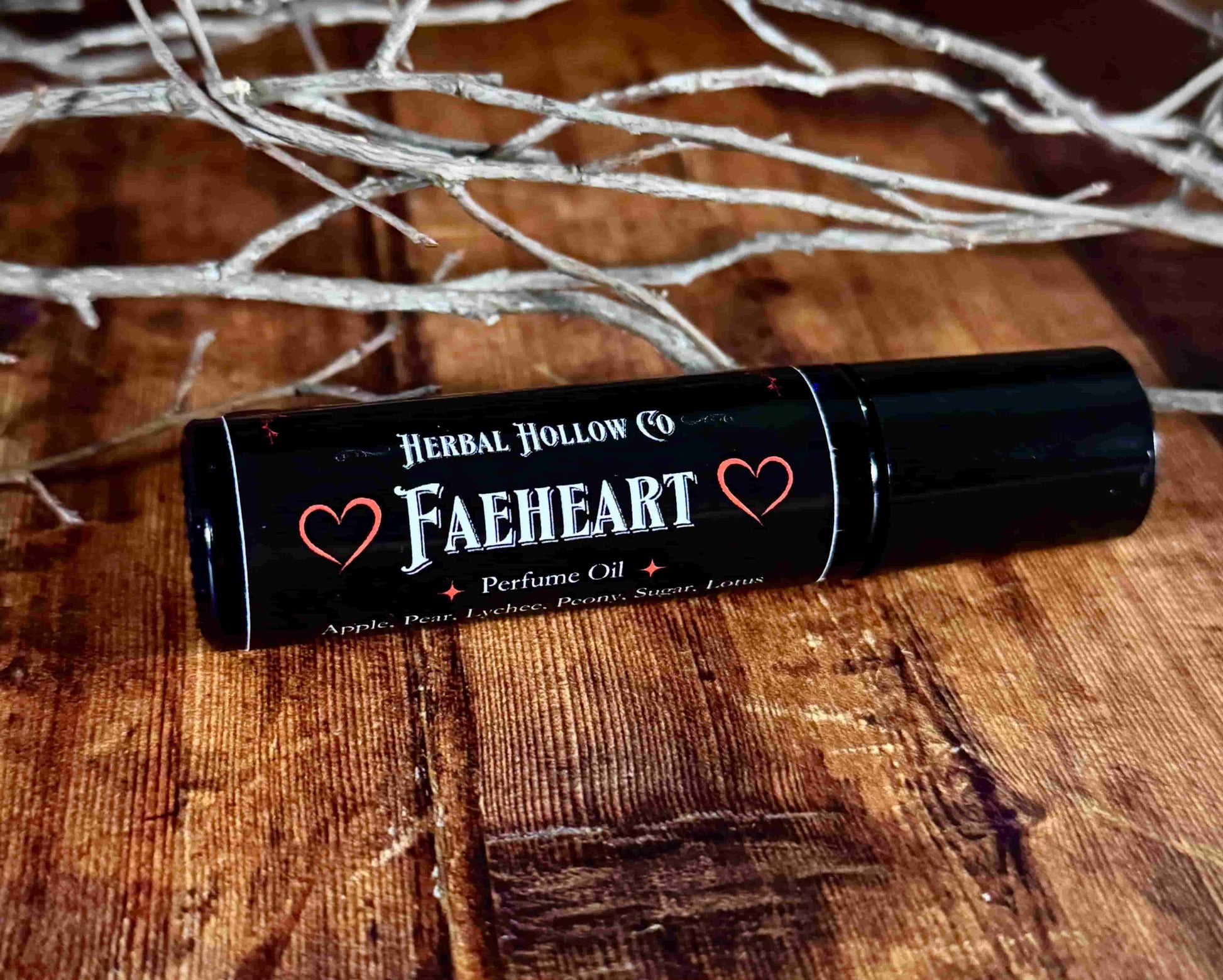 Image of small perfume bottle lying down. Faeheart is a fantasy-inspired rollerball fragrance oil perfume, featuring a handcrafted magical lychee, pear, apple, peony, and lotus flower scent.