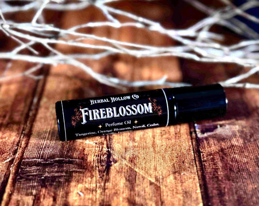 Image of small perfume bottle lying down. Fireblossom is a fantasy-inspired rollerball fragrance oil perfume, featuring a handcrafted magical neroli, tangerine, bergamot, orange blossom, jasmine, heliotrope, vanilla, cedar, sea salt, and sandalwood scent.