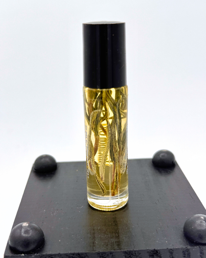 Rollerball perfume bottle with rosemary leaves labeled 'Protection' with black cap on a white background on top of a black surface.
