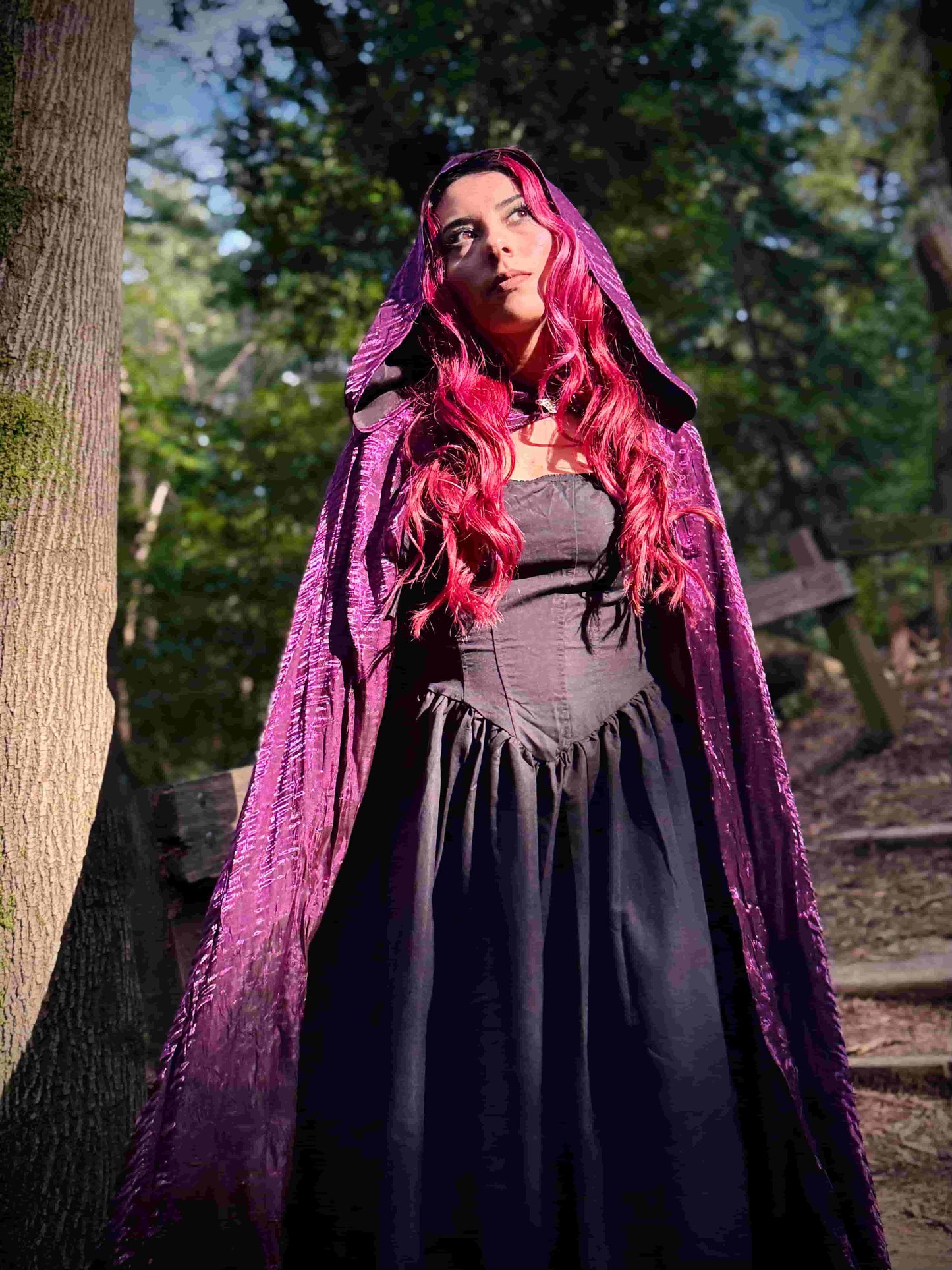 Person with red hair wearing a purple cloak in a forest setting