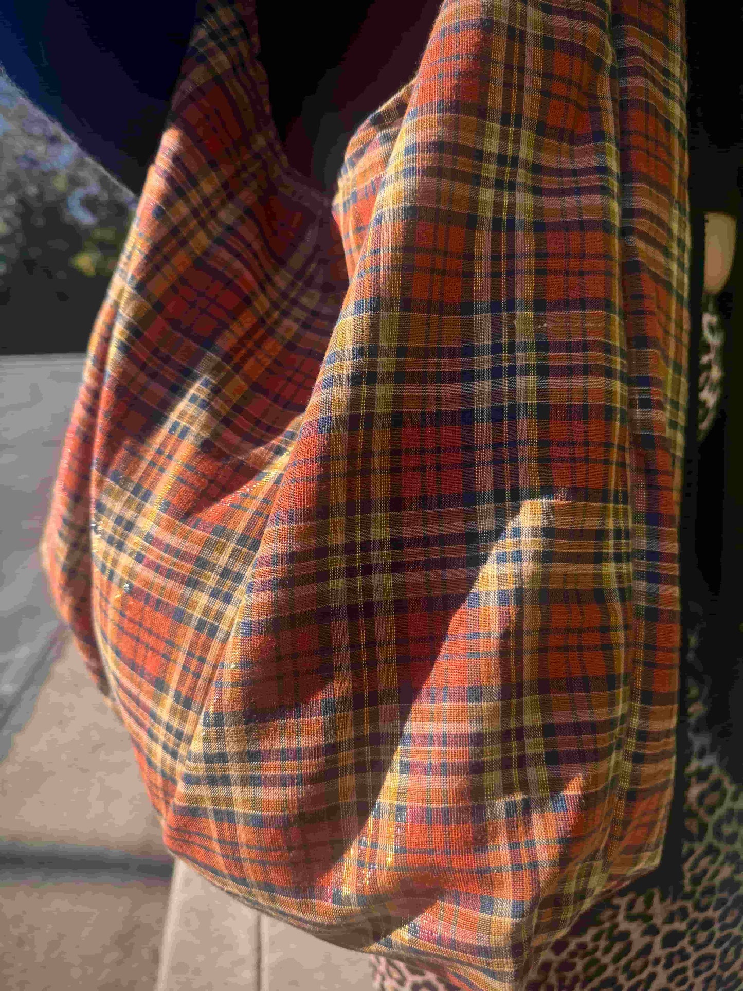 Close-up of a plaid fabric slouchy bag with orange, grey, and red colors.