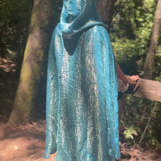 Person wearing a sky blue cloak in a forest