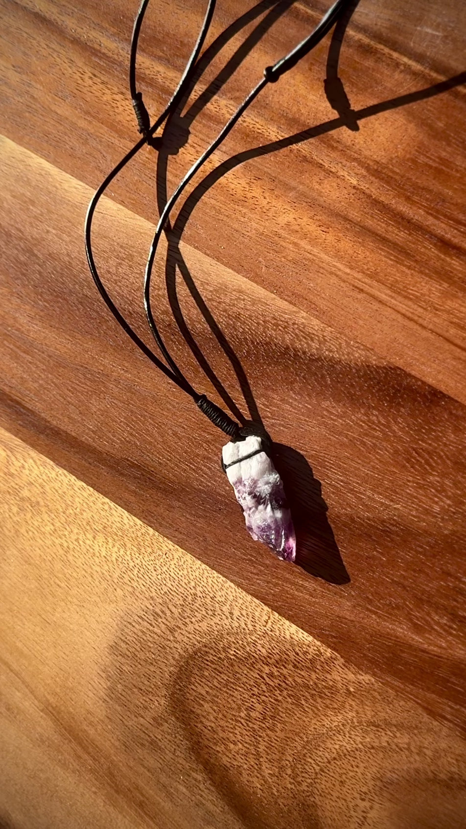 Large rough cut white and purple Amethyst crystal necklace on a wooden surface, spinning.