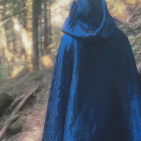 Video of handmade enchanting short and long iridescent lightweight capes in a forest, perfect for renaissance fairs, fantasy costumes, and magical cottagecore fashion.
