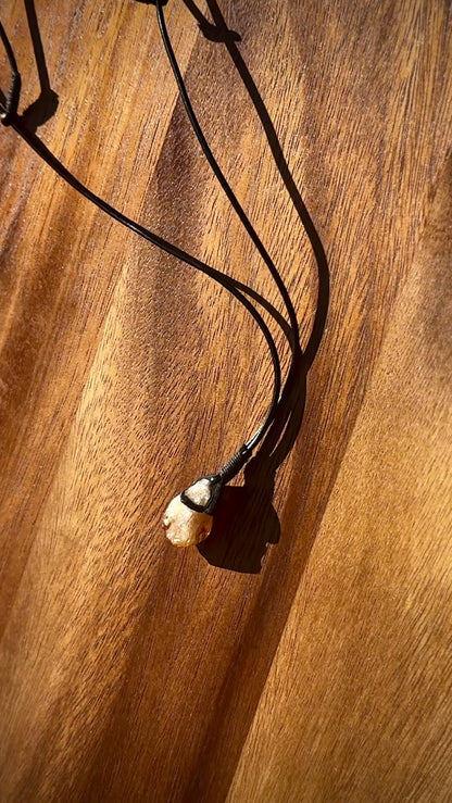 citrine crystal with leather necklace band on a wooden table, spinning