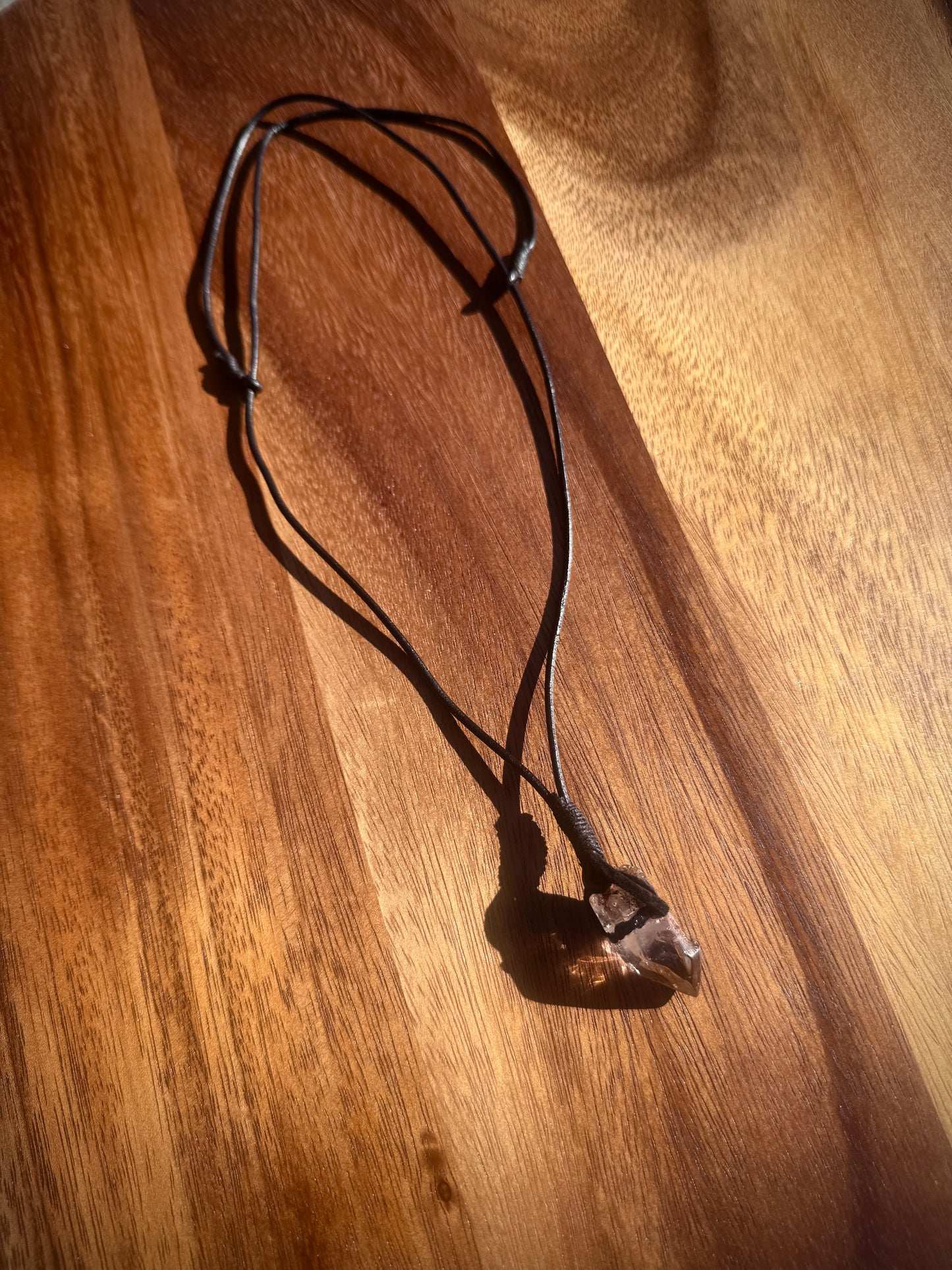 Necklace with a Quartz crystal on a wooden surface