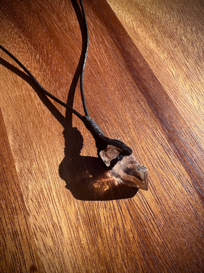 Crystal pendant on a leather cord on a wooden surface