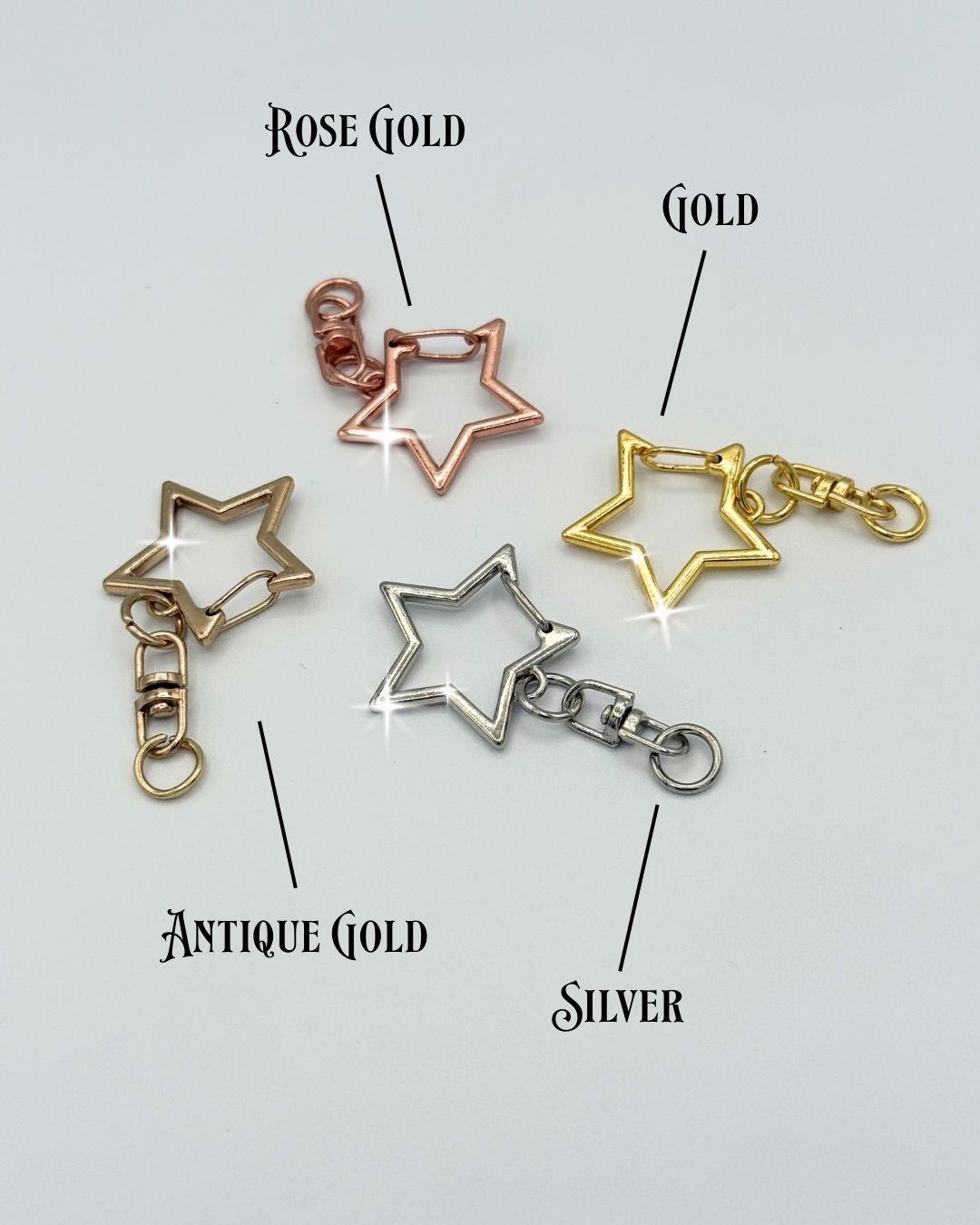 Star-shaped keychain clasps in rose gold, gold, antique gold, and silver on a light gray background.