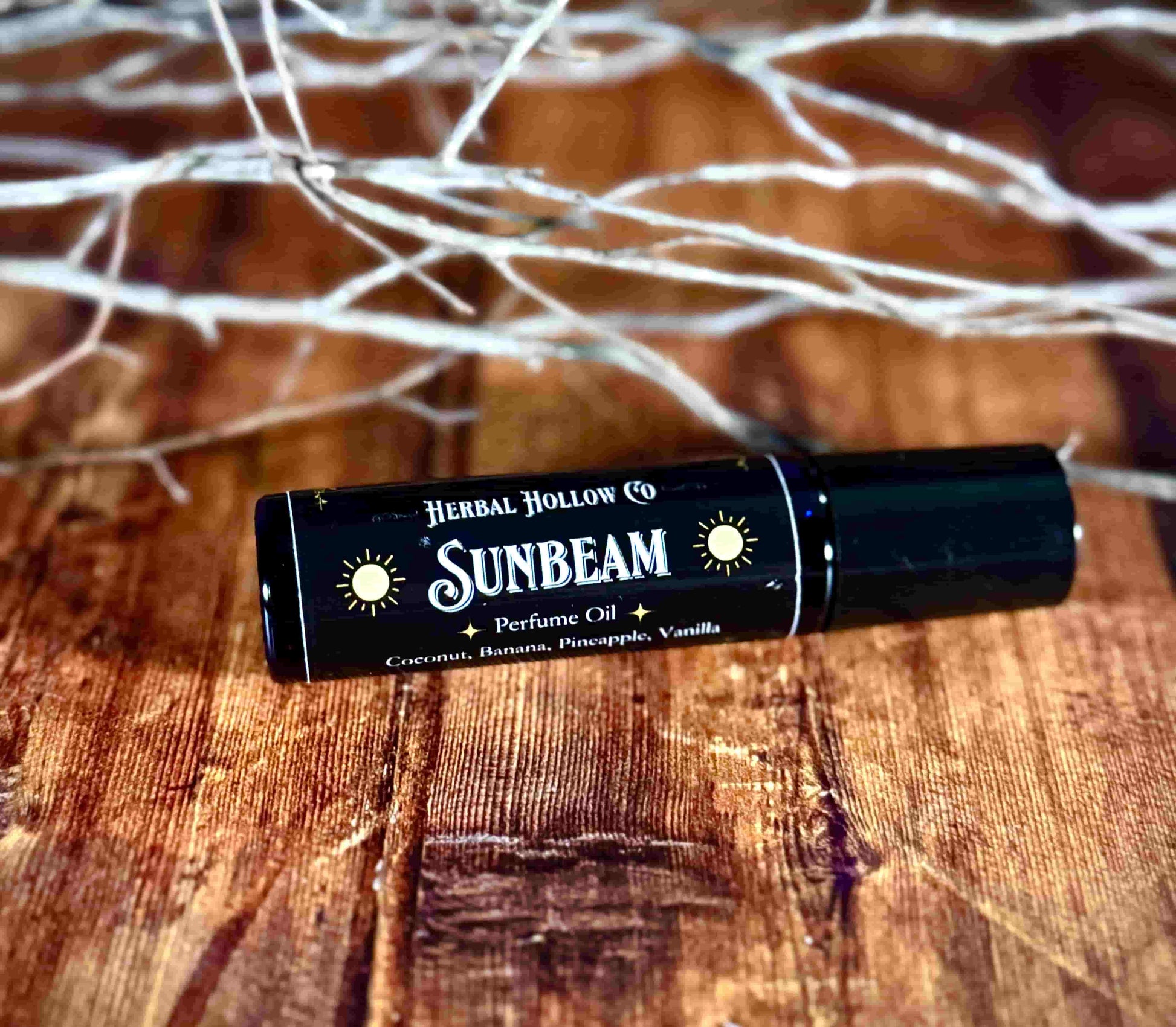 Image of small perfume bottle lying down. Sunbeam fantasy-inspired rollerball fragrance oil perfume, featuring a handcrafted magical coconut, pineapple, vanilla and banana scent.